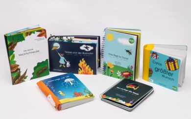Sechs Tastbücher mit farbenfrohen Covern. Zwei liegen im Vordergrund, vier sind stehend im Hintergrund platziert.